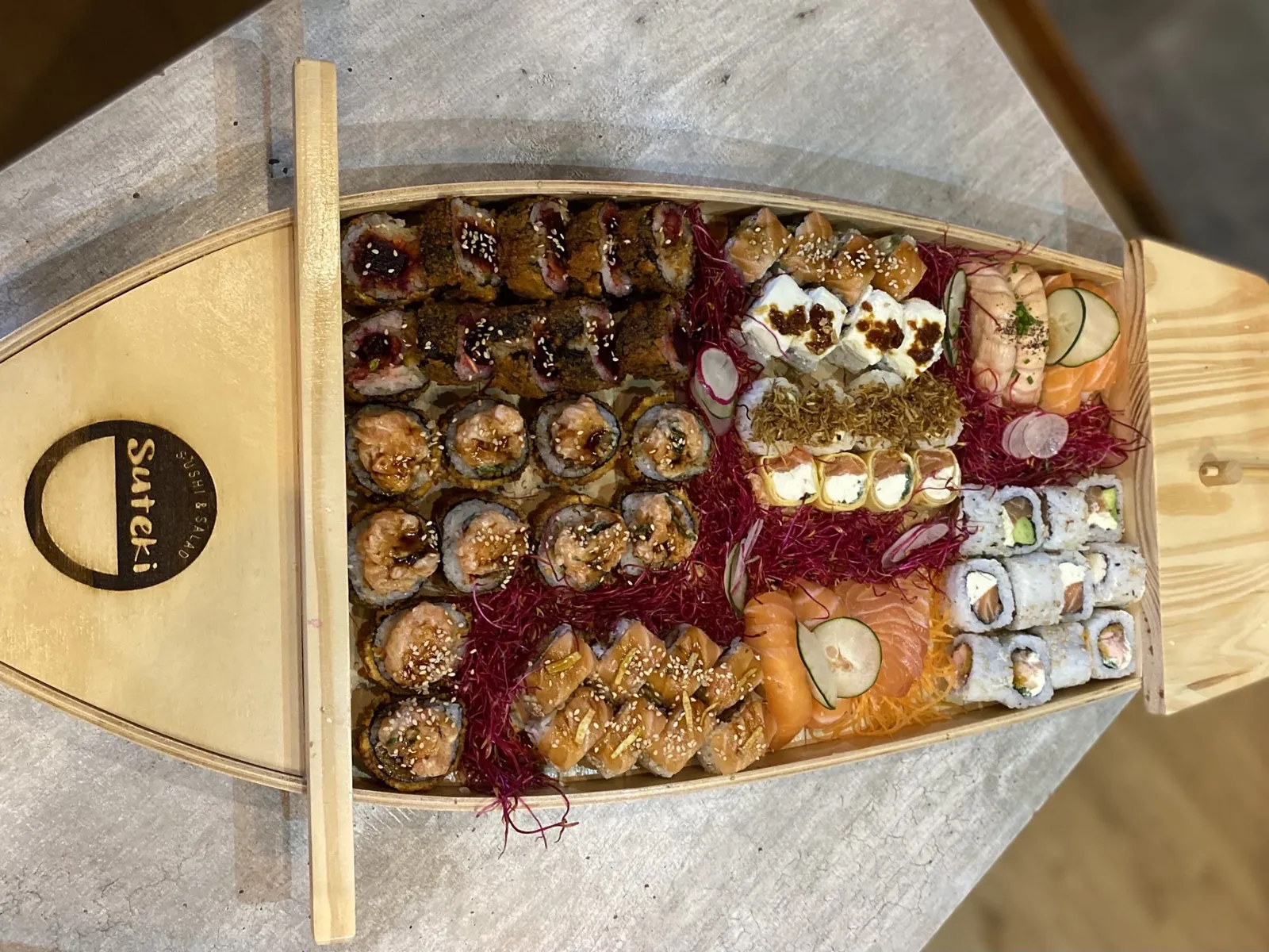 Barcos de madera de Suteki cargados de rolls, niguiris y sashimi de salmón, listos para la mesa