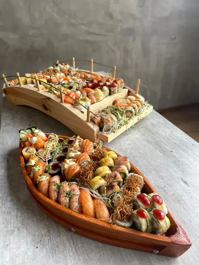 Barco de madera y puente japonés llenos de rolls, nigiris de salmón y piezas de colores